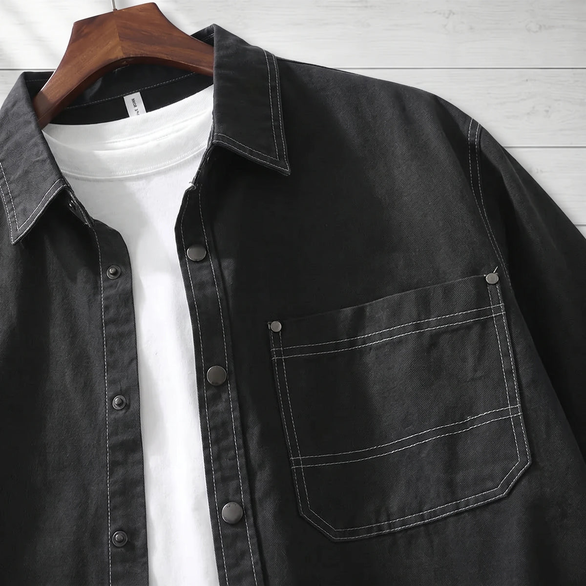 Close-up of the pocket, snaps and white stitching on a black workwear shirt