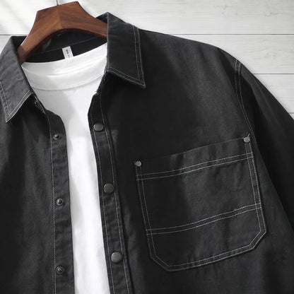 Close-up of the pocket, snaps and white stitching on a black workwear shirt