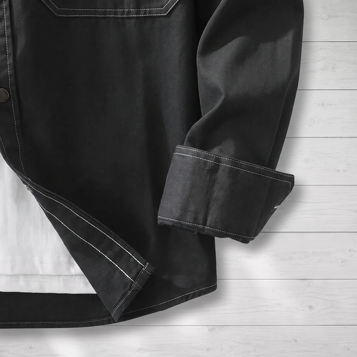 Close-up of the folded cuff and contrast stitching on a black workwear shirt