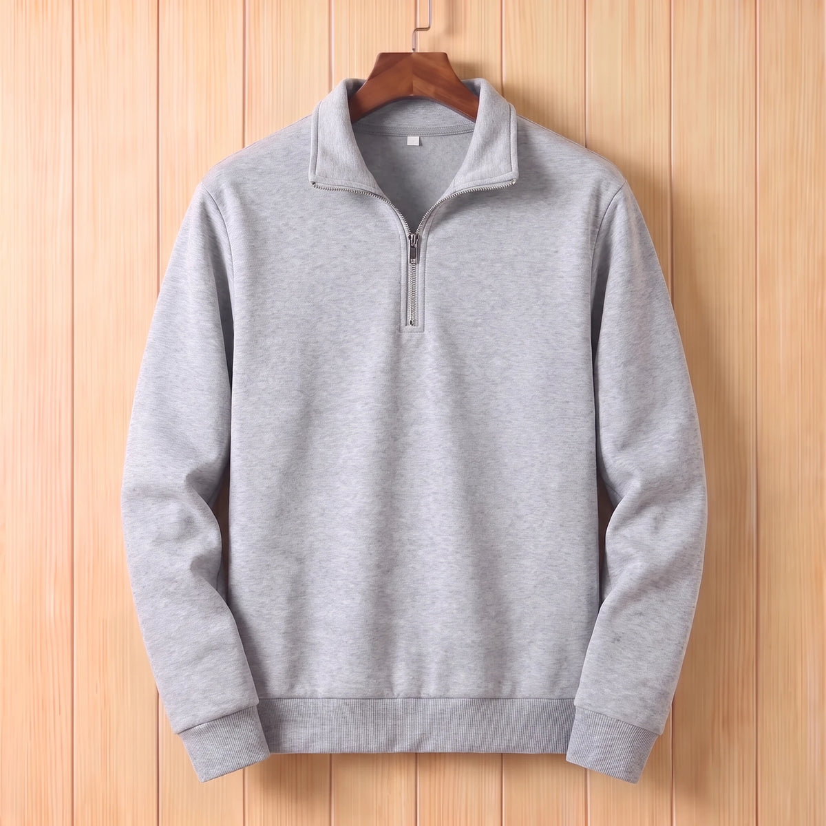 Light grey half zip sweater with a folded collar and ribbed cuffs hanging on a wooden hanger