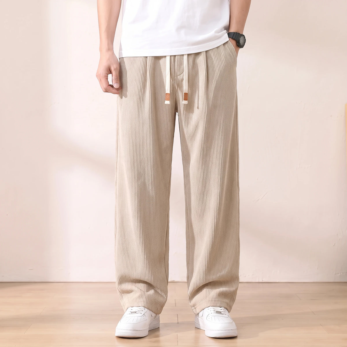 Beige pleated corduroy trousers with a white drawstring worn with a white tee and sneakers