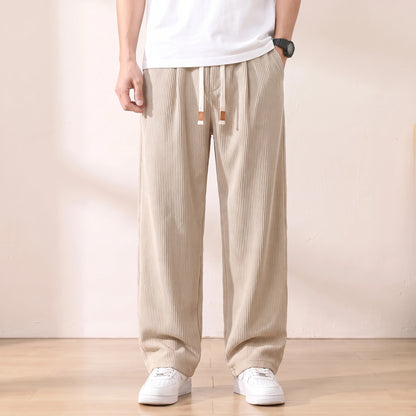 Beige pleated corduroy trousers with a white drawstring worn with a white tee and sneakers