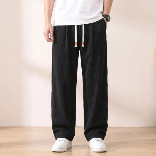 Black pleated corduroy trousers with a white drawstring worn with a white tee and sneakers