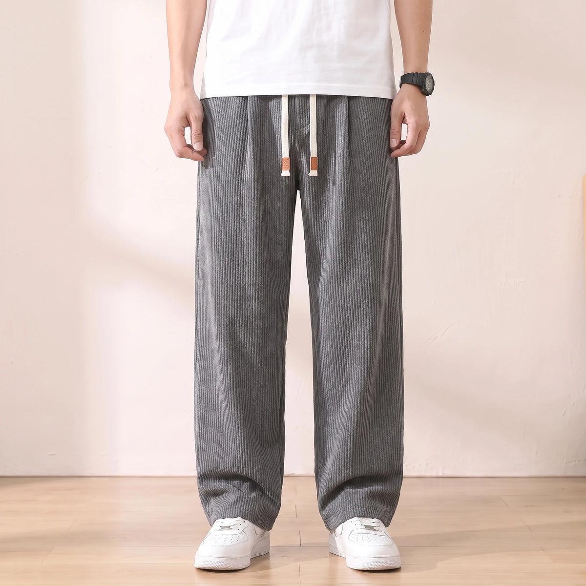 Grey pleated corduroy trousers with a white drawstring worn with a white tee and sneakers