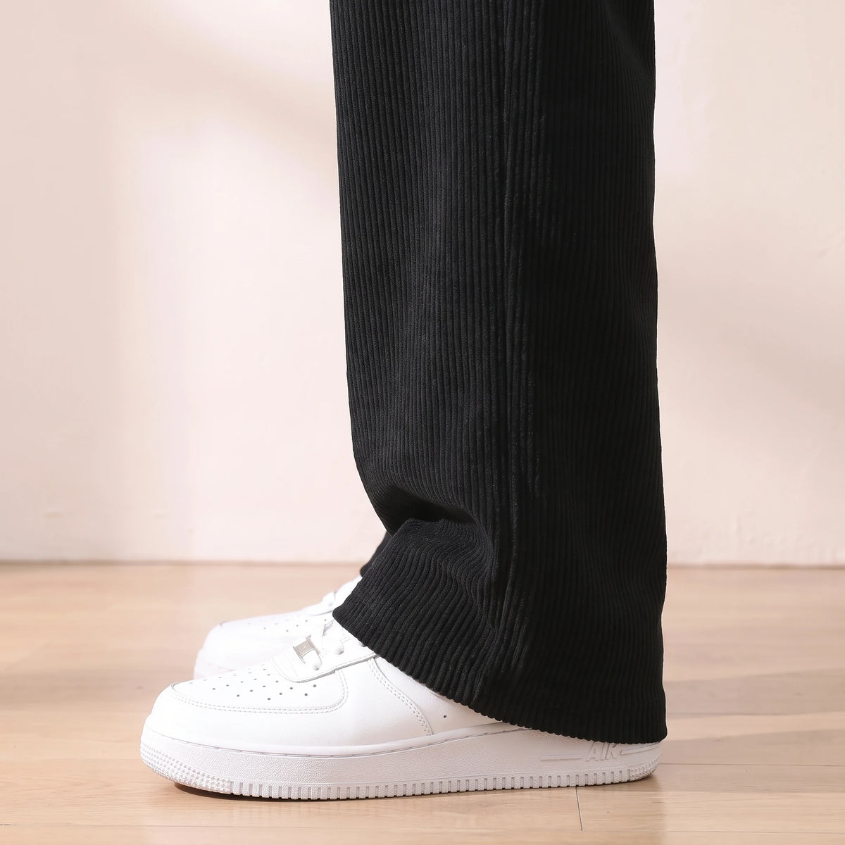 Close-up of the fine corduroy ribs on the lower leg and hem of the black trousers