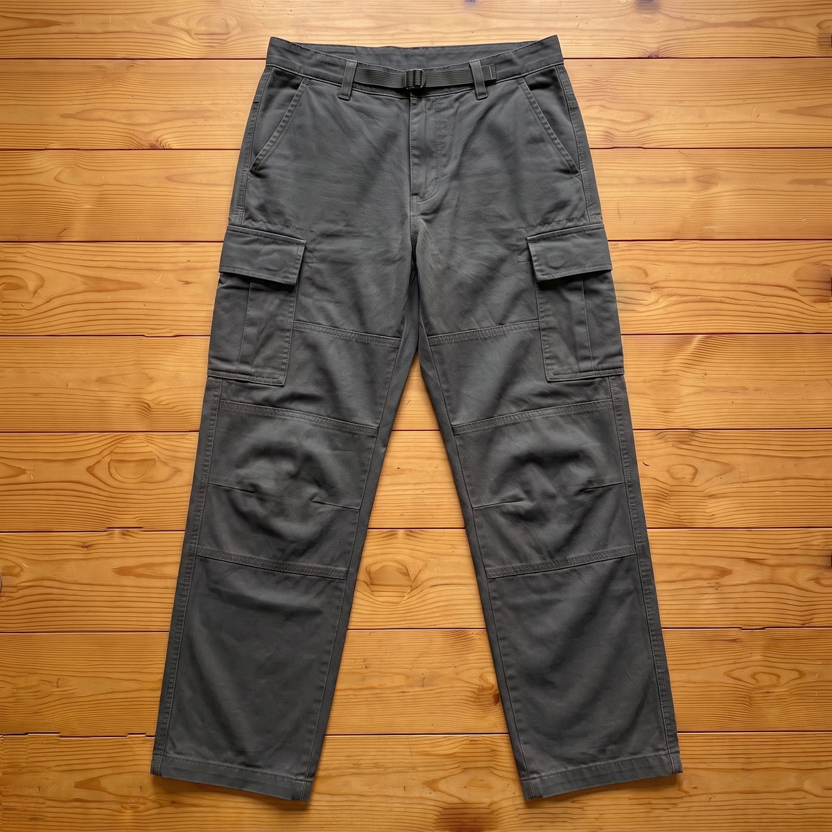 Grey relaxed cargo trousers laid flat on pine wood