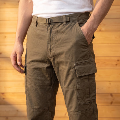 Man wearing brown relaxed cargo trousers with a hand in the pocket