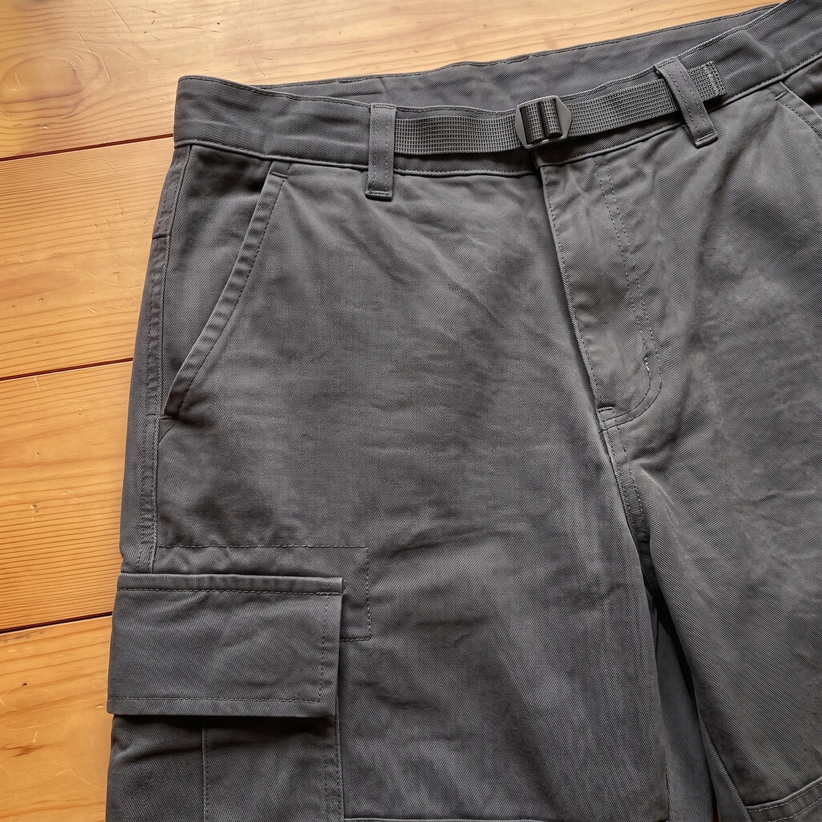 Close-up of the waist strap and flap pocket on grey cargo trousers