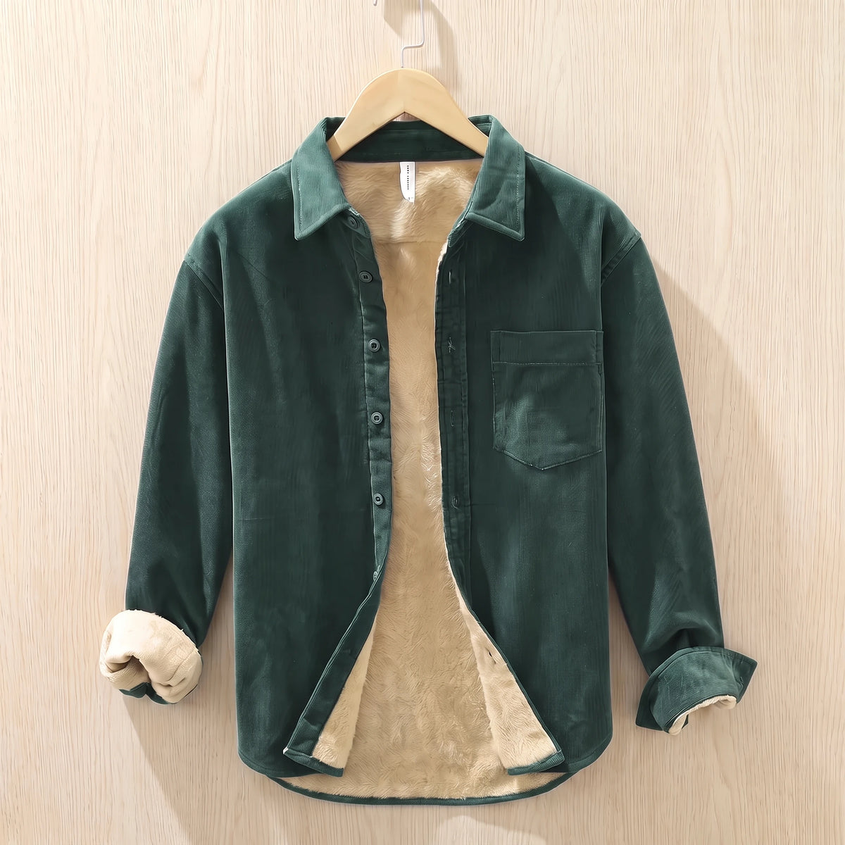 Forest green fleece lined corduroy shirt with a chest pocket hanging on a wooden hanger