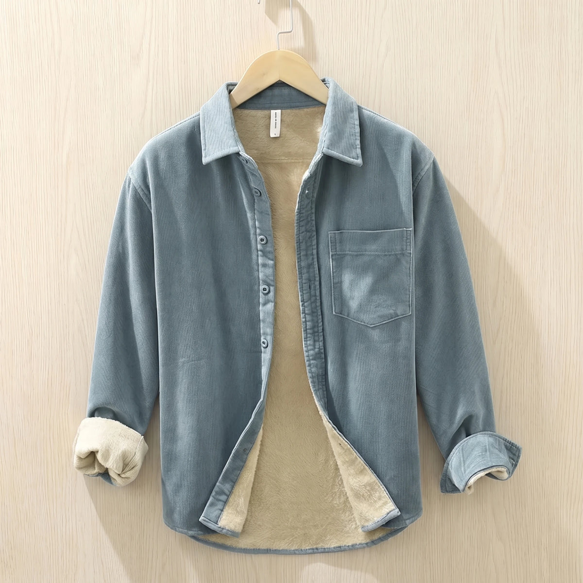 Light blue fleece lined corduroy shirt with a chest pocket hanging on a wooden hanger