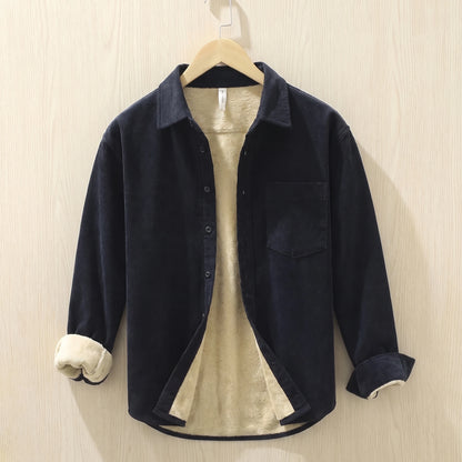 Navy fleece lined corduroy shirt with a chest pocket hanging on a wooden hanger