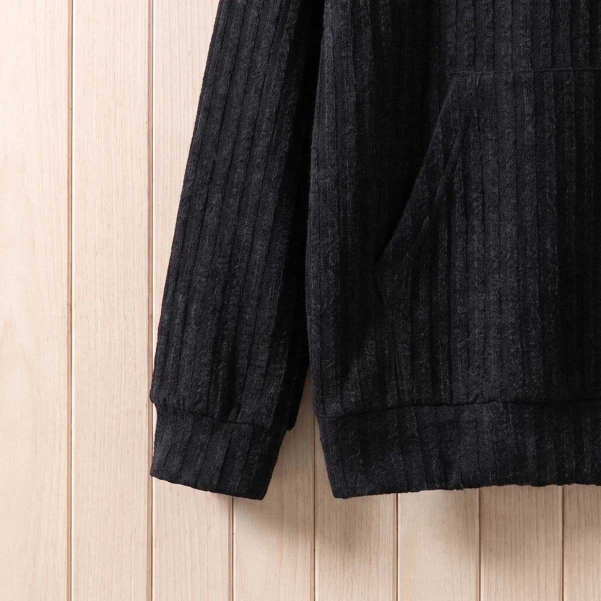 Close-up of the ribbed cuff and hem on the black knit hooded sweater