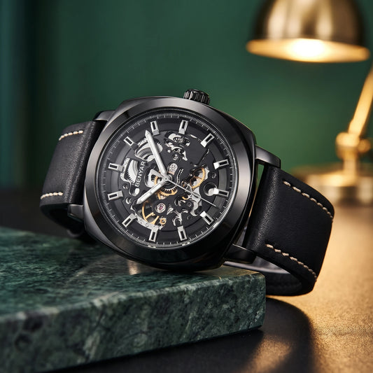 Men's all-black skeleton automatic watch resting on green marble
