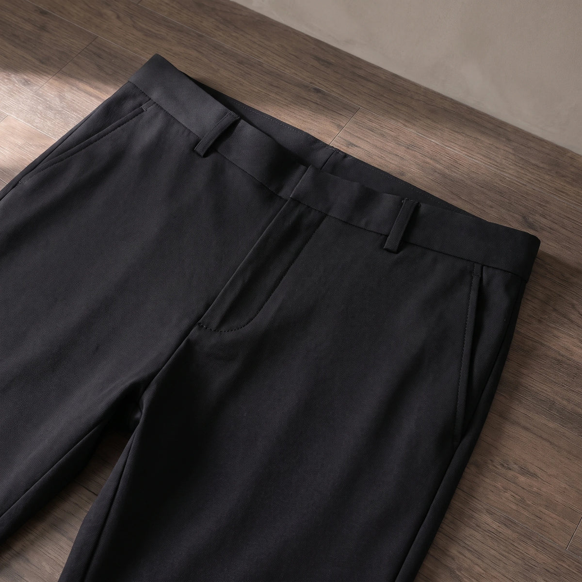 Close-up of the waistband, belt loops and pocket of the black trousers