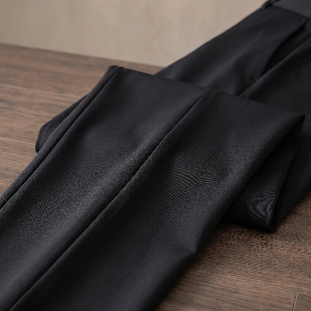 Close-up of the smooth fabric and crease of the black trousers