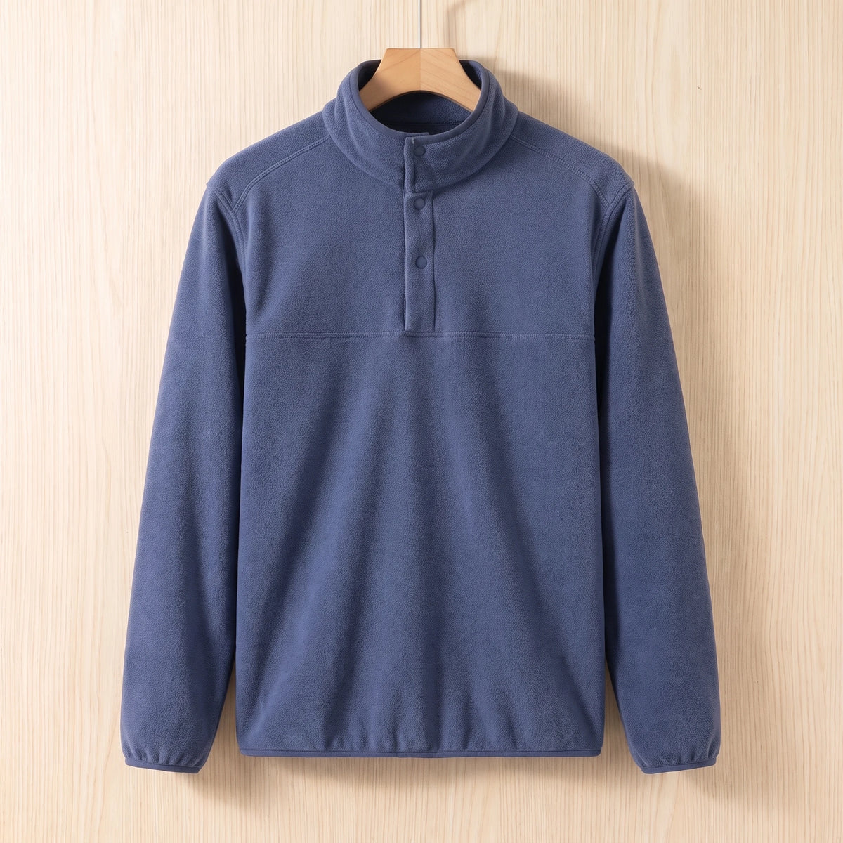 Blue fleece pullover with a snap collar and elastic cuffs hanging on a wooden hanger