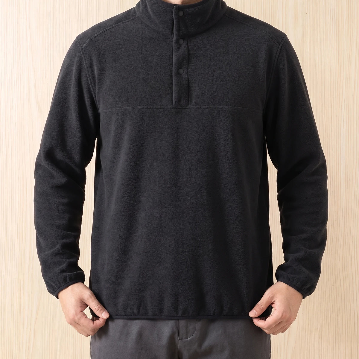 Man wearing a black snap collar fleece pullover with dark grey trousers