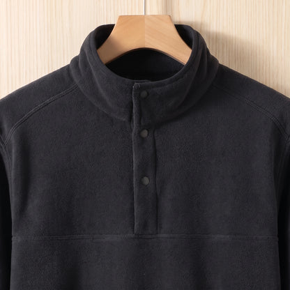 Close-up of the stand collar and three snap buttons on a black fleece pullover