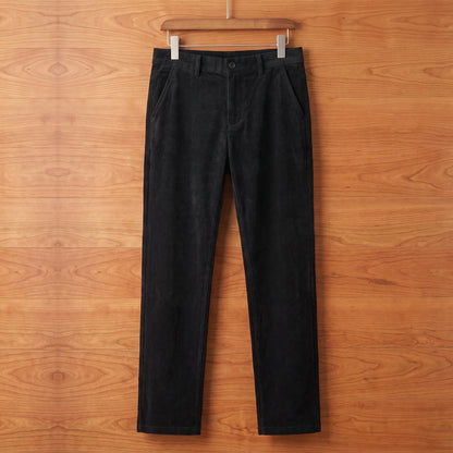 Black straight corduroy trousers hanging on a cherry wood wall