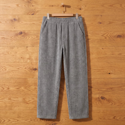 Grey thick rib corduroy trousers hanging on an oak wall