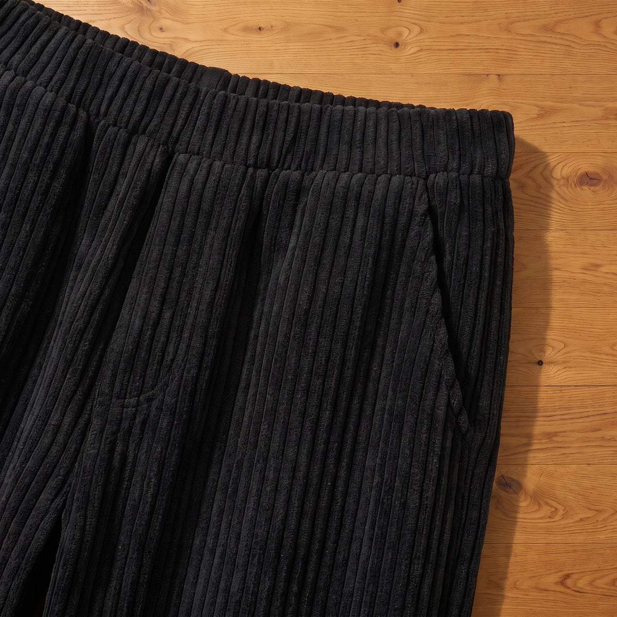Close-up of the stretch waist and side pocket on black corduroy trousers