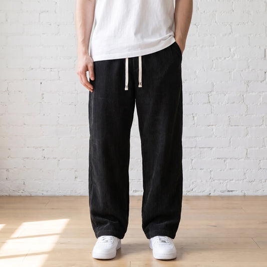 Black wide corduroy trousers with a white drawstring worn with a white tee and sneakers