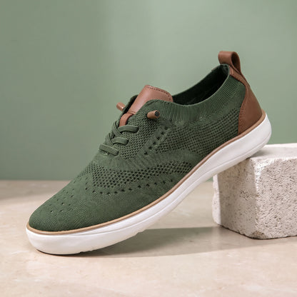 Green knit lace-up shoe with a white sole on a limestone block