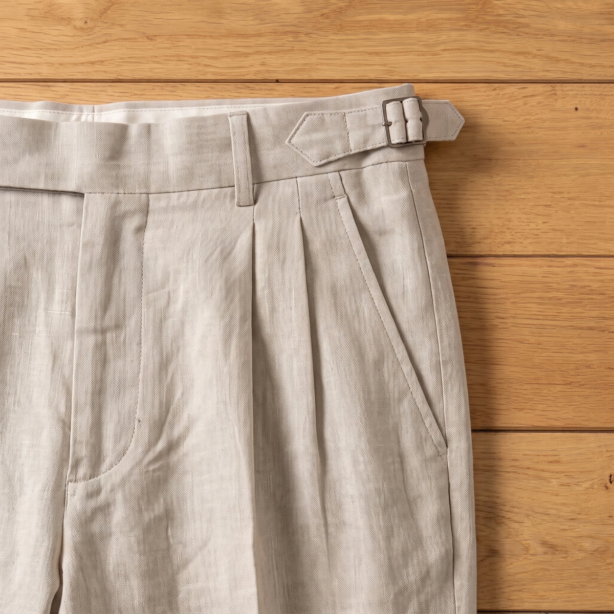 PLEATED LINEN TROUSERS side buckle and pleat close-up